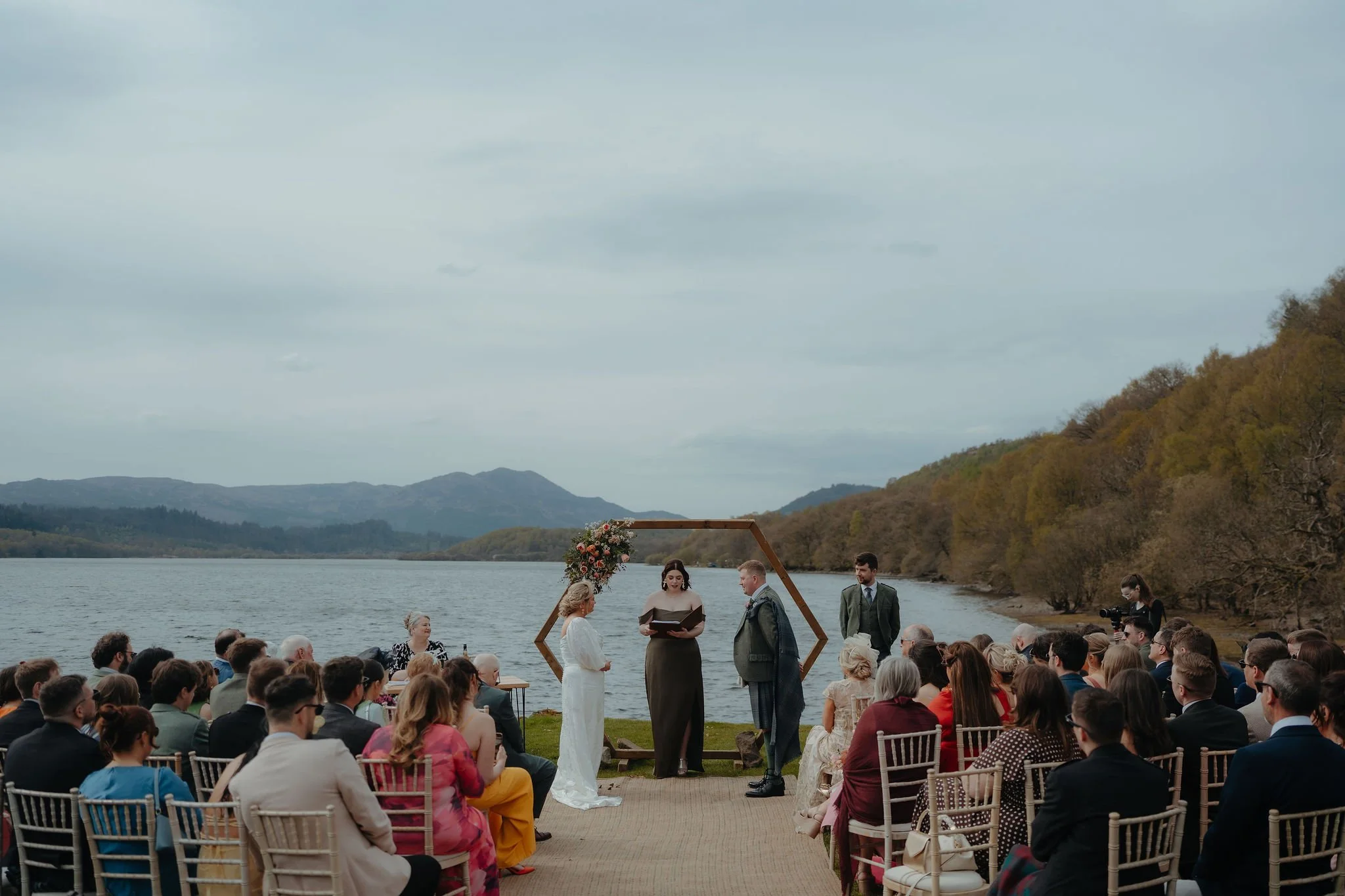 Ceremony underway on the lawn with guests seated by the water